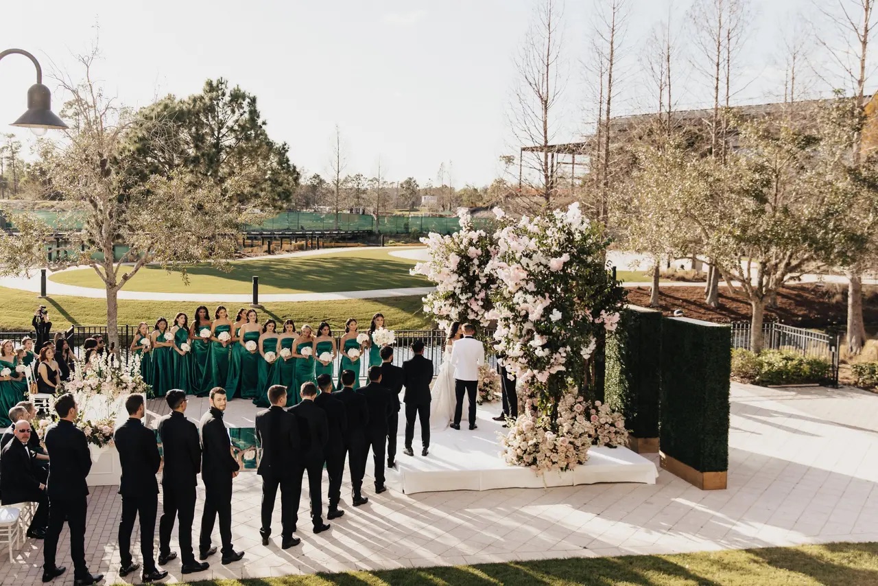 A sweeping view of an outdoor wedding party beneath floral installations
