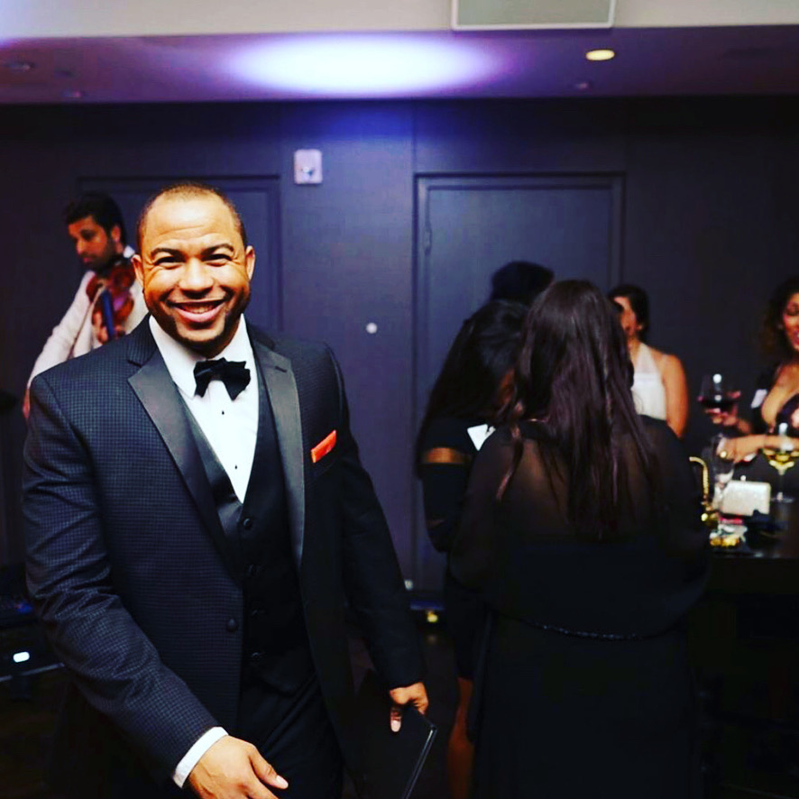 Pastor Wayde smiling in a tuxedo at a wedding reception