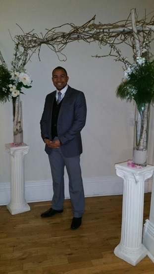 Pastor Wayde standing beneath a floral ceremony arch