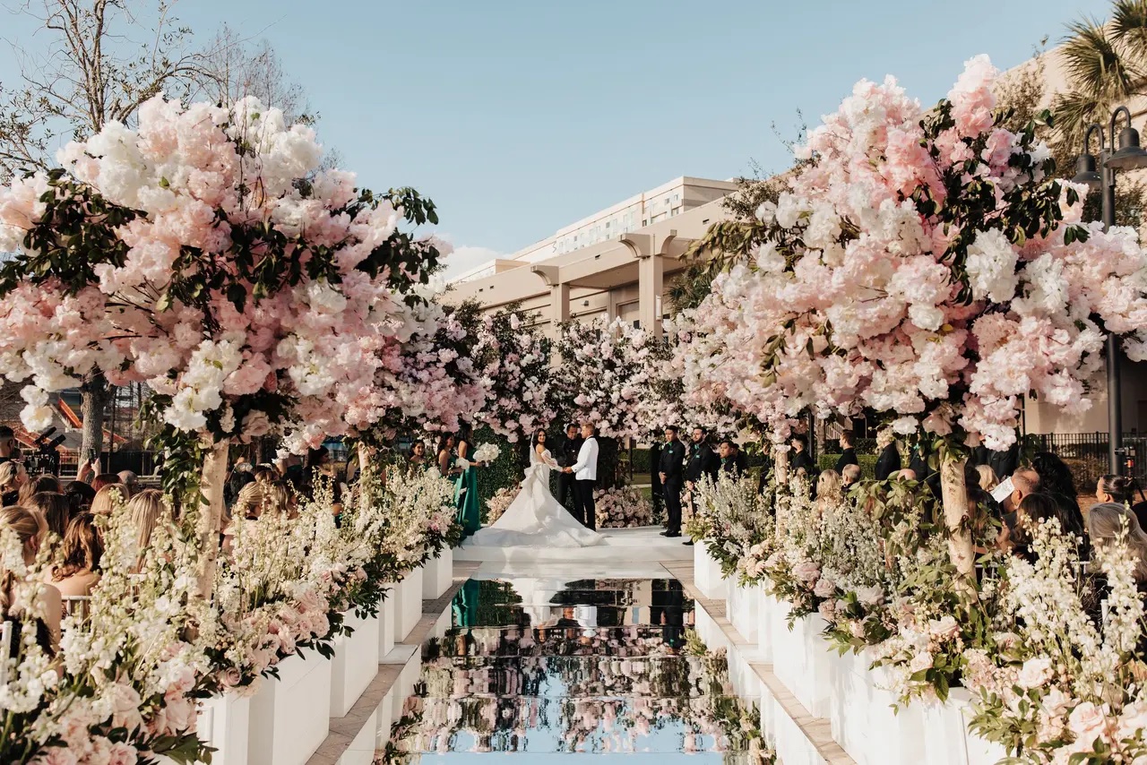 A luxury outdoor ceremony framed by abundant blush florals