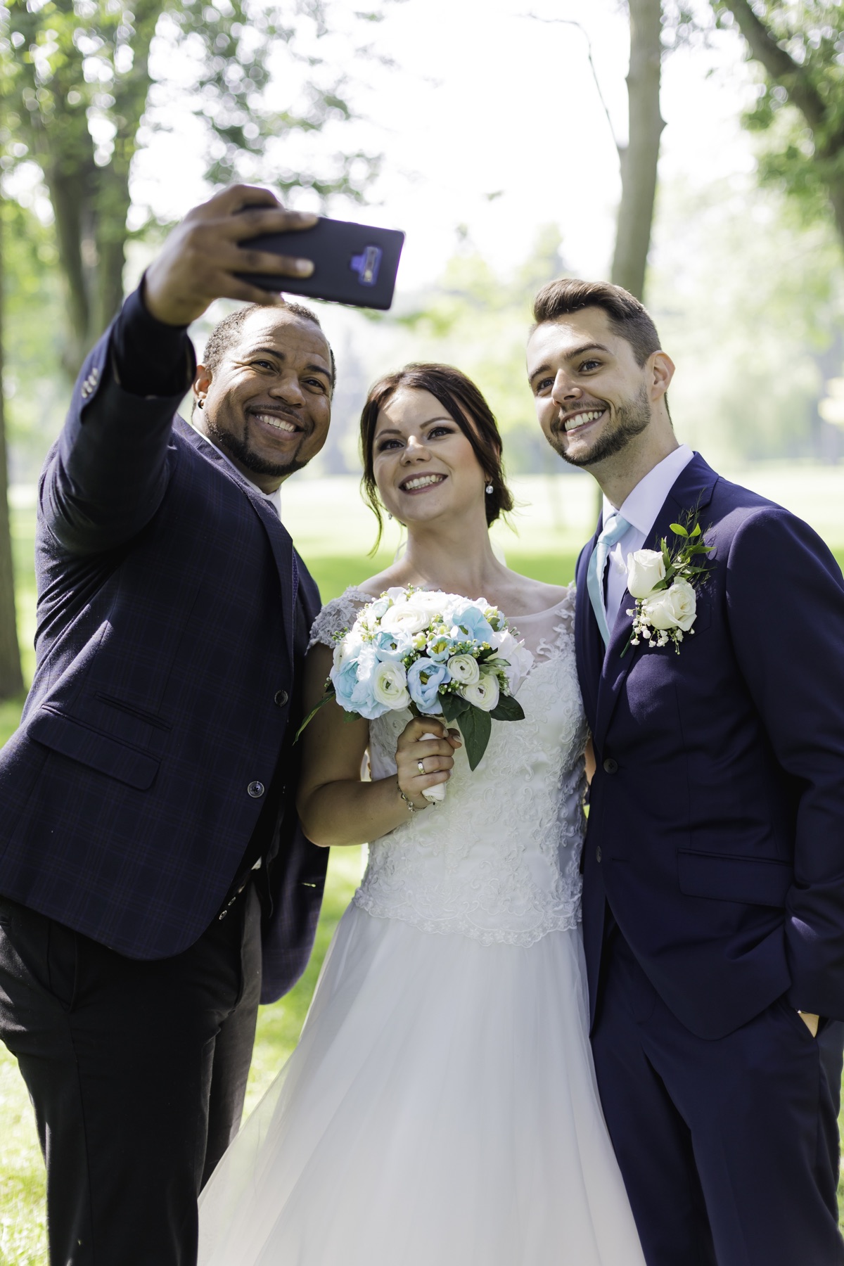 Wayde taking a joyful selfie with newlyweds outdoors