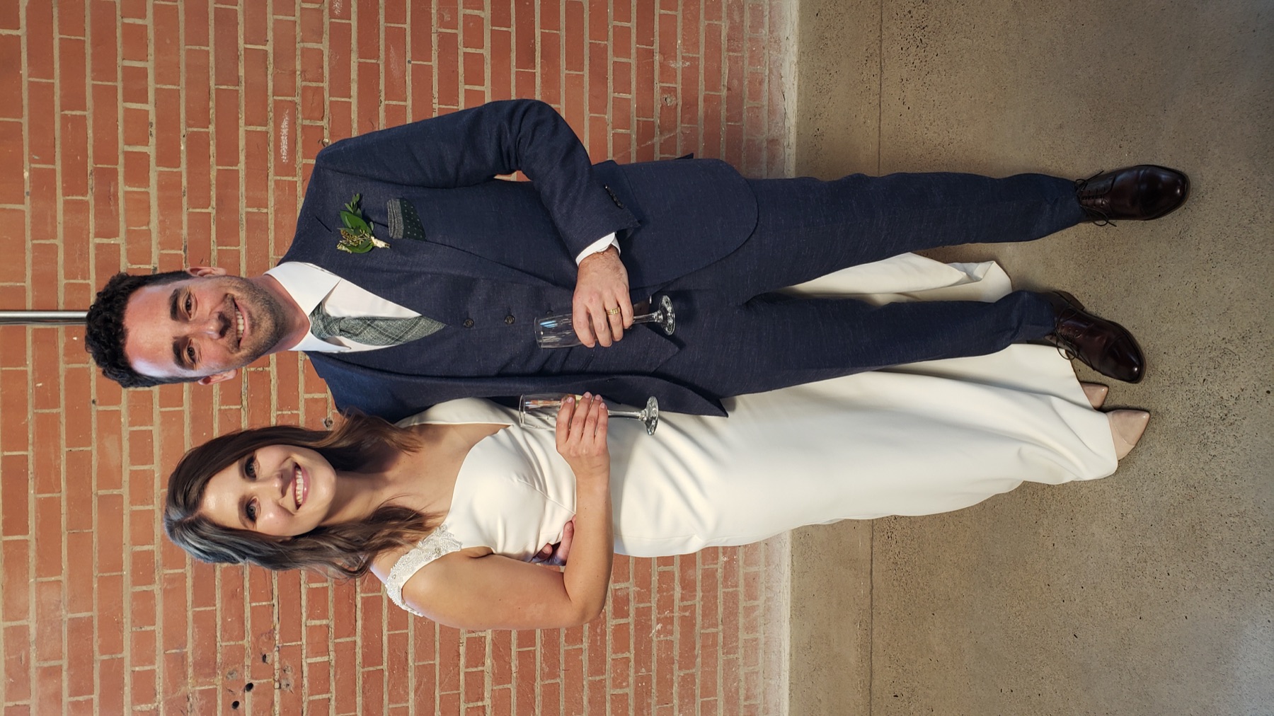 Newlyweds celebrating against an architectural brick backdrop