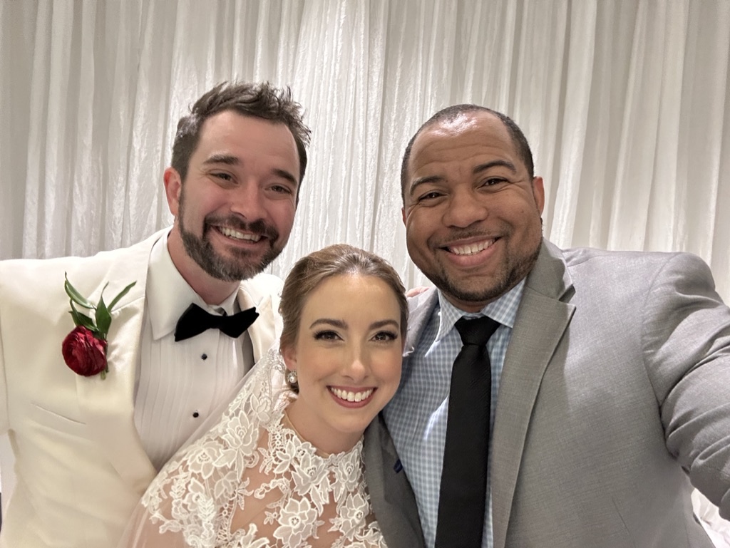 Wayde smiling with newlyweds after their ceremony