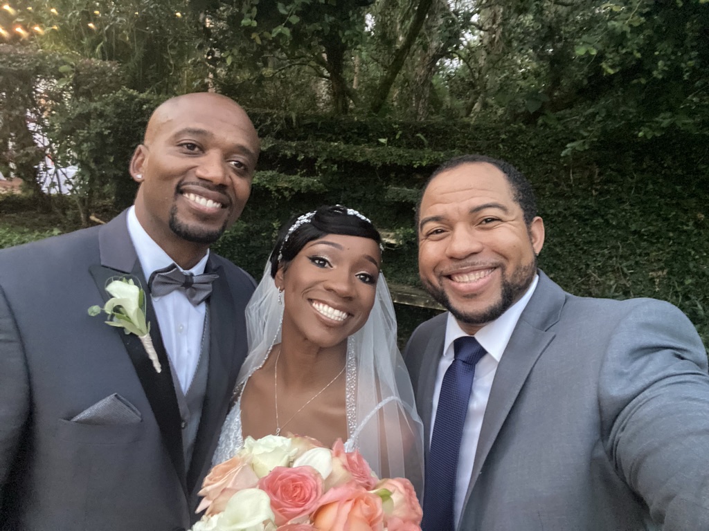Wayde celebrating with newlyweds outdoors