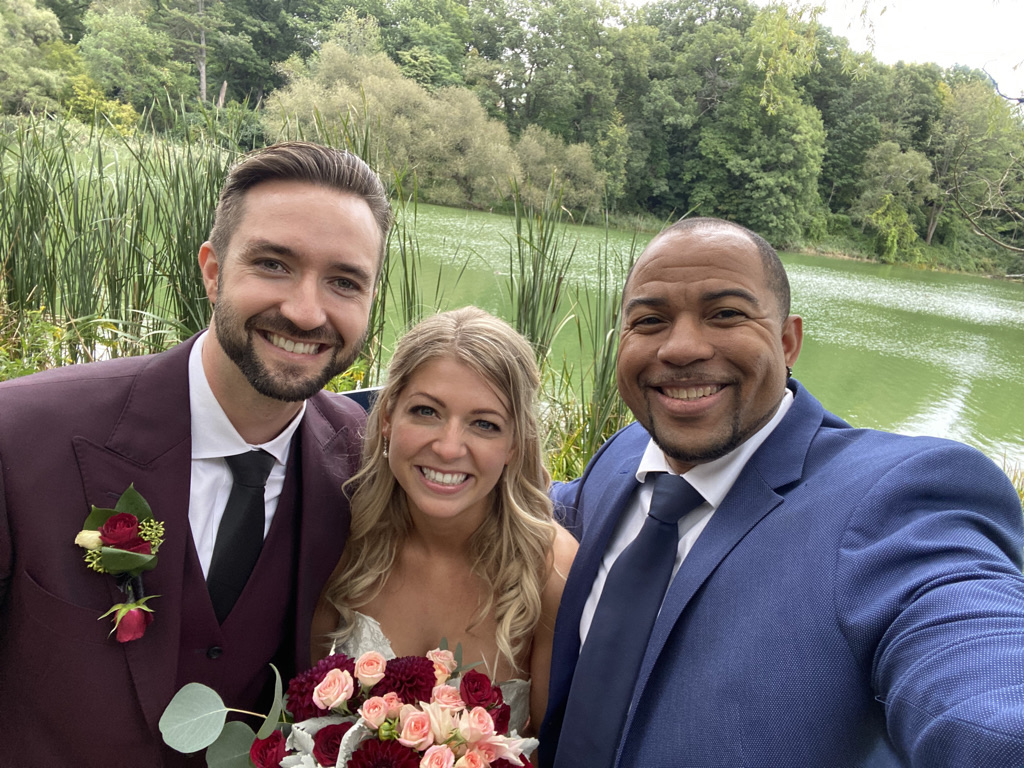 Wayde celebrating with newlyweds beside a lakeside ceremony