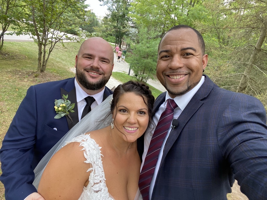 Wayde and newlyweds smiling after a woodland ceremony