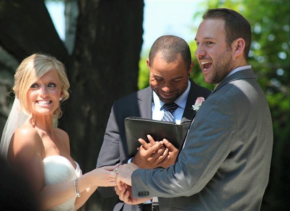 Wayde laughing with a couple during their outdoor ceremony
